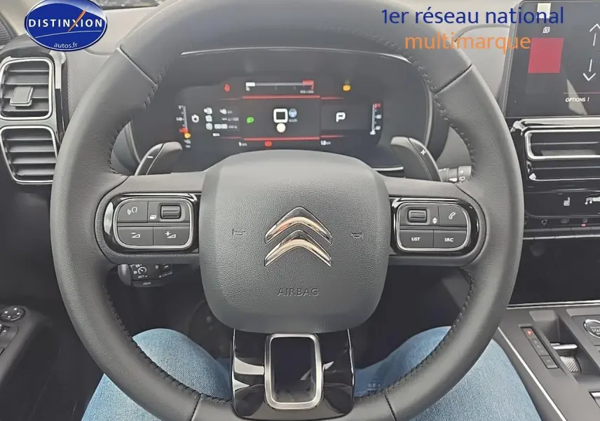 Vue rapprochée du volant cuir noir du Citroën C5 Aircross 2025 avec tableau de bord numérique et commandes intégrées.