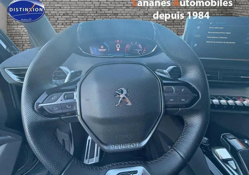 Vue rapprochée du volant cuir perforé Peugeot 3008 GT 2023 avec commandes intégrées et tableau de bord numérique.