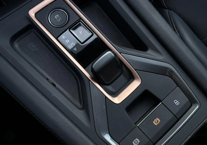 Gros plan sur la console centrale noire avec levier de vitesse électronique et cadre cuivré dans une CUPRA Leon 2025.