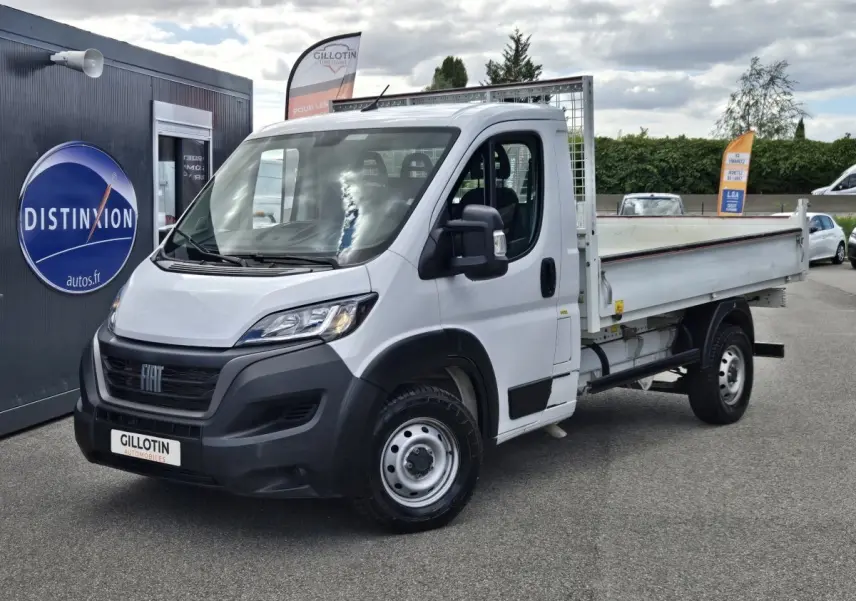 Fiat Ducato Fourgon blanc en vue 3/4 avant droit, plateau arrière ouvert avec grille de protection.