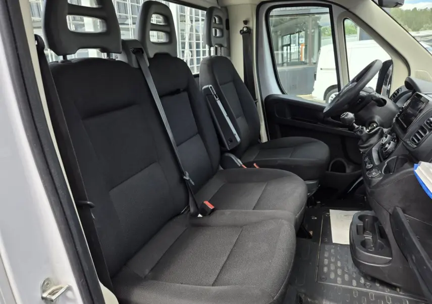Vue intérieure côté conducteur du Fiat Ducato Fourgon blanc 2022, montrant les sièges noirs et le tableau de bord.