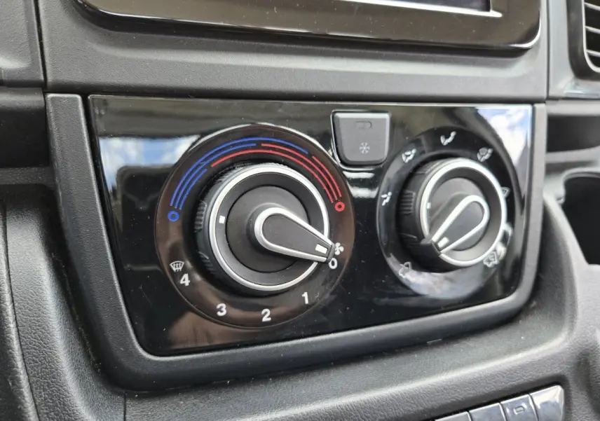 Gros plan sur les commandes de climatisation du tableau de bord noir du Fiat Ducato Fourgon blanc 2022.