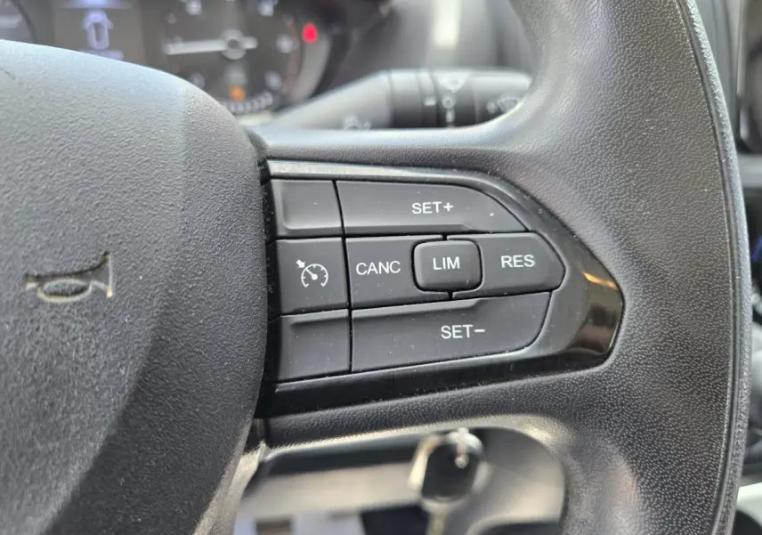 Gros plan sur les commandes du régulateur de vitesse au volant noir du Fiat Ducato Fourgon blanc, version 2022.