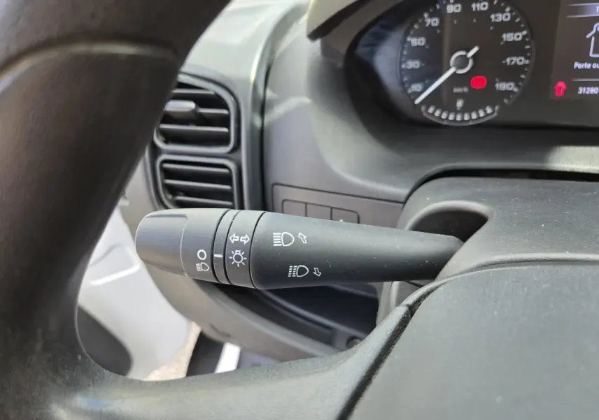 Gros plan sur la commande des phares à gauche du volant dans l’habitacle du Fiat Ducato Fourgon blanc 2022.