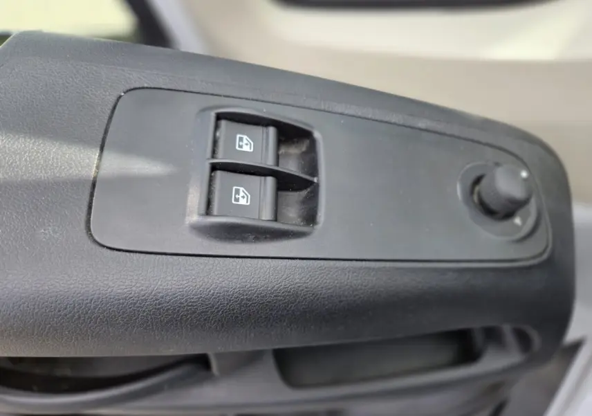 Gros plan sur les commandes de lève-vitres et réglage des rétroviseurs côté conducteur du Fiat Ducato Fourgon blanc 2022.
