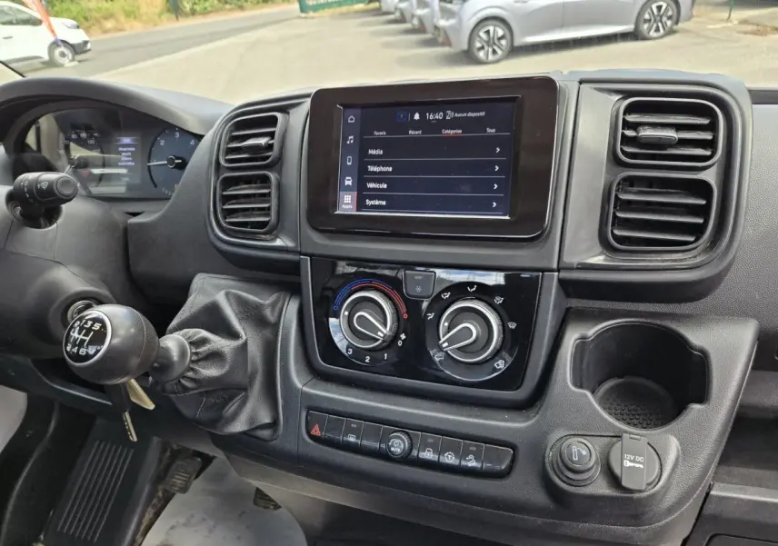 Vue rapprochée du tableau de bord noir du Fiat Ducato Fourgon 2022 avec écran tactile et commande de climatisation.