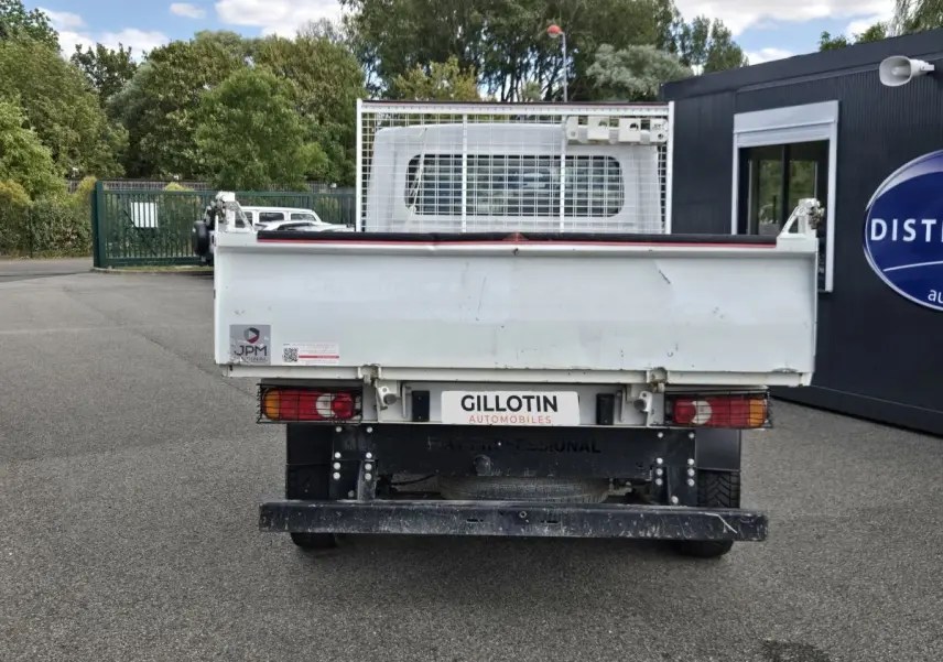 Vue arrière d’un FIAT Ducato Fourgon blanc avec benne basculante et grille de protection, stationné en extérieur.