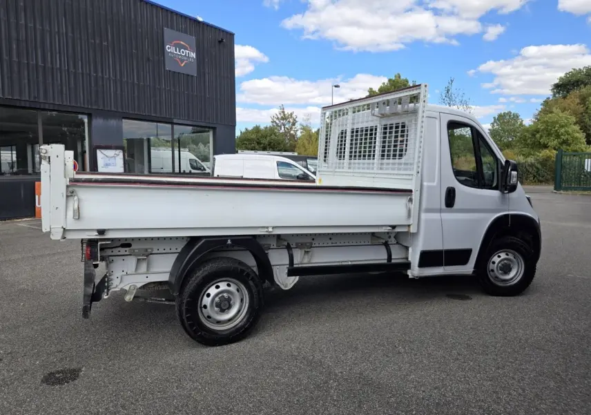 FIAT Ducato Fourgon blanc vu de profil côté droit, plateau arrière avec grille de protection sur cabine.