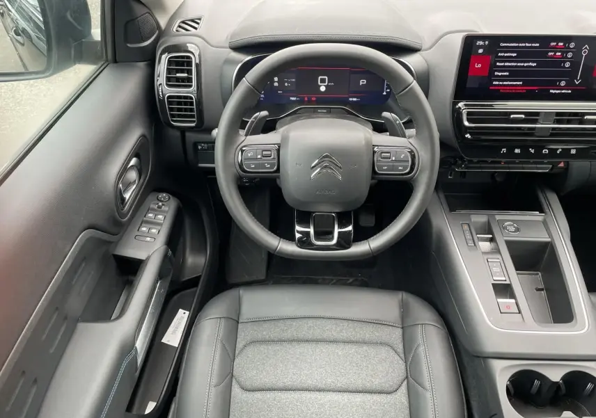 Vue intérieure avant du Citroën C5 Aircross 2025 noir, volant cuir multifonction et écran tactile central visible.
