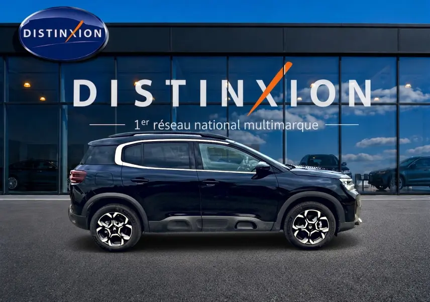 Profil droit du Citroën C5 Aircross noir 2025 avec jantes alu et barres de toit devant vitrine Distinxion.