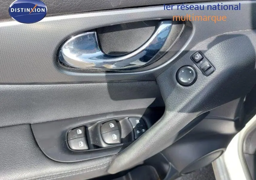 Poignée de porte intérieure côté conducteur du Nissan Qashqai blanc lunaire, avec commandes électriques des vitres et rétroviseurs.