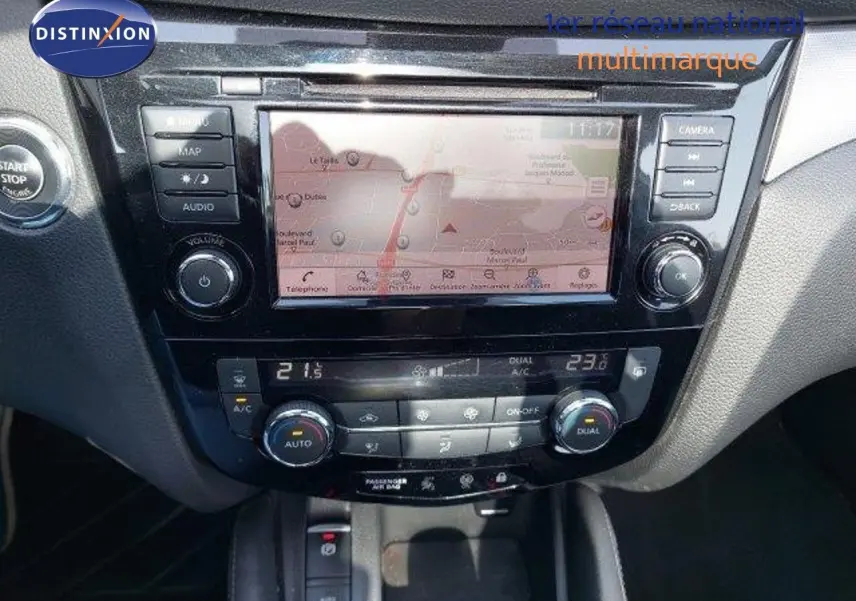 Tableau de bord du Nissan Qashqai blanc lunaire, affichant l'écran tactile central et la climatisation automatique.