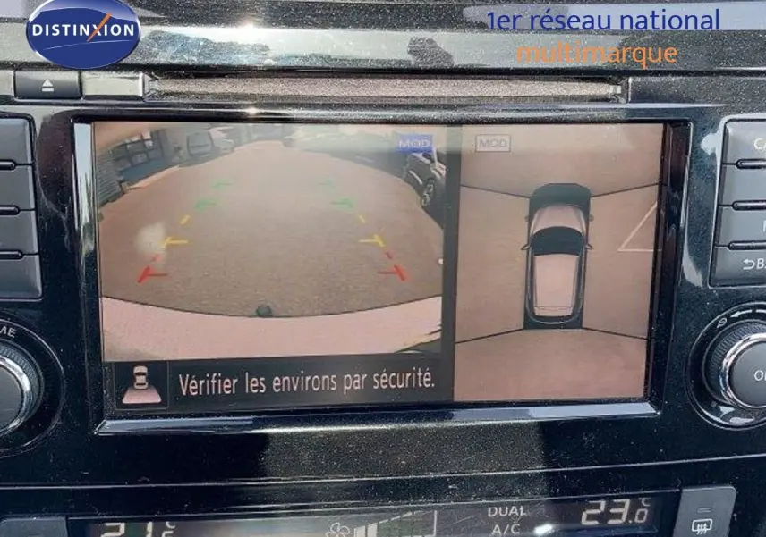 Écran multimédia montrant la caméra de recul et vue 360° du Nissan Qashqai blanc lunaire, tableau de bord en noir brillant.