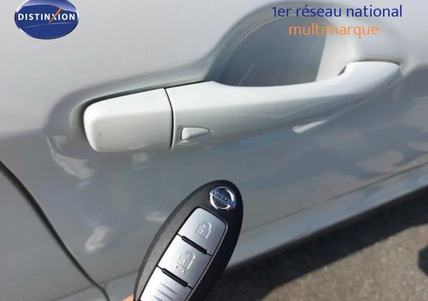 Gros plan sur la poignée de porte côté gauche d'un Nissan Qashqai blanc lunaire avec une clé mains libres visible.