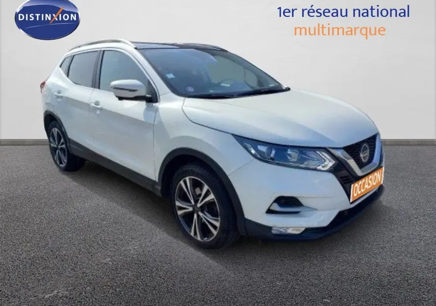 Nissan Qashqai blanc lunaire en 3/4 avant droit, avec jantes alliage bicolores et calandre noire distinctive.