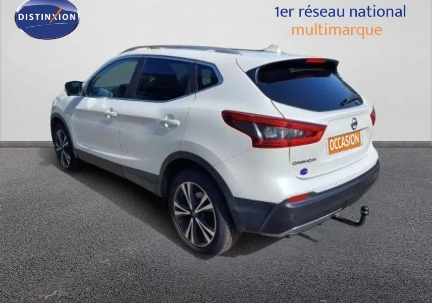 Nissan Qashqai blanc lunaire vu en 3/4 arrière droit avec attelage et jantes biton 18 pouces.