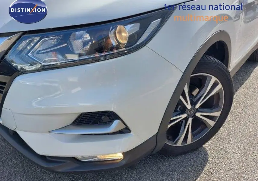 Gros plan sur l'avant droit blanc lunaire métal du Nissan Qashqai 2019 avec phares et jante biton visibles.