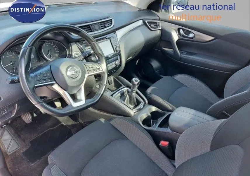 Intérieur du Nissan Qashqai 2019 vu côté conducteur, tableau de bord noir avec boîte manuelle et sièges tissu gris.