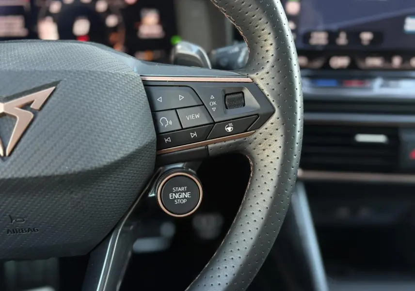 Gros plan sur le volant perforé noir de la CUPRA Leon 2025 avec bouton Start Engine Stop et commandes intégrées.