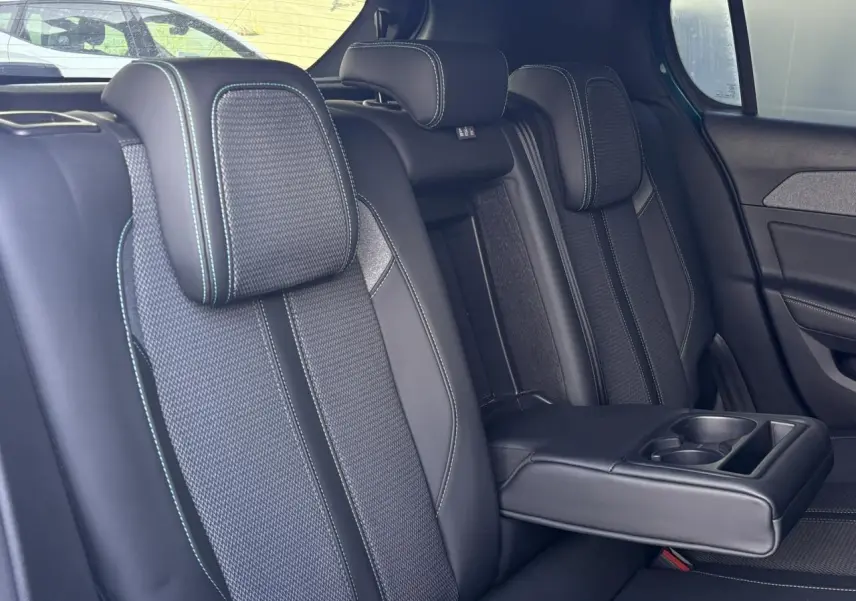 Vue intérieure des sièges arrière de la Peugeot 308 2024, sellerie tri matières noire avec surpiqûres bleues et accoudoir central déployé.