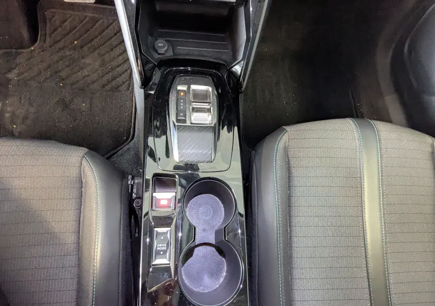 Vue plongeante sur la console centrale noire brillante du Peugeot 2008 1.5 BlueHDi, avec levier de vitesses et porte-gobelets.