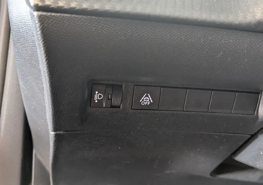 Gros plan sur les commandes de réglage des phares et d'activation de l'alerte de franchissement de ligne dans un Peugeot 2008 bleu.