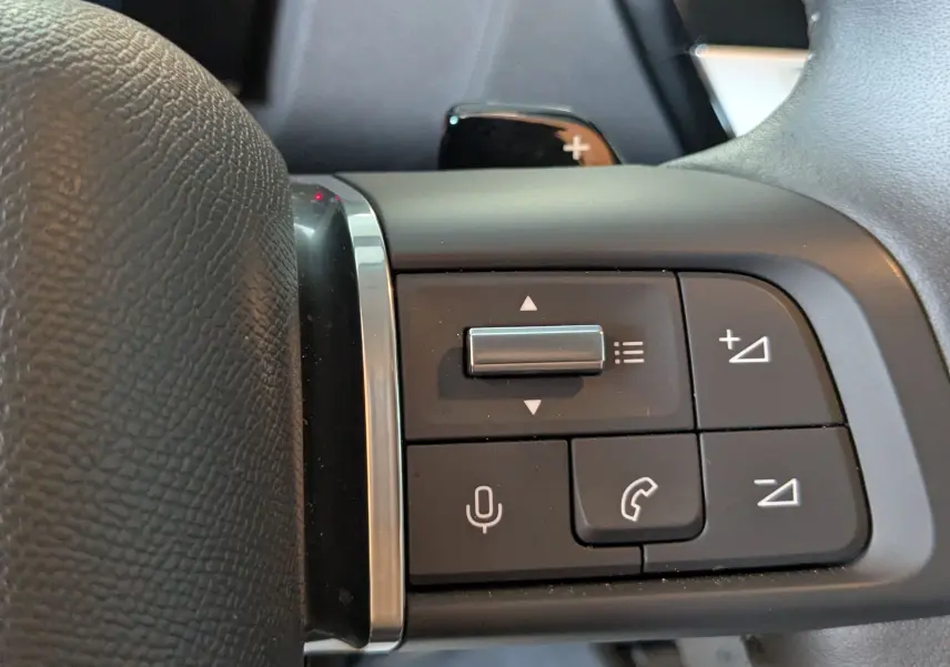 Gros plan sur les commandes au volant côté gauche du Citroën C4 Hybrid 145 gris Mercury, boutons multifonctions visibles.