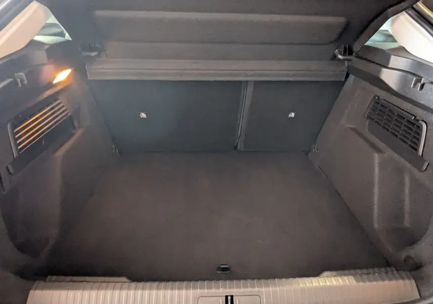 Coffre ouvert de la Citroën C4 Hybrid 145 gris Mercury, montrant un espace de chargement propre et éclairé à gauche.