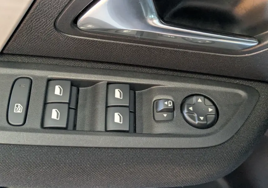 Gros plan sur les commandes des vitres et rétroviseurs côté conducteur d'une Citroën C4 Hybrid 145 gris Mercury.