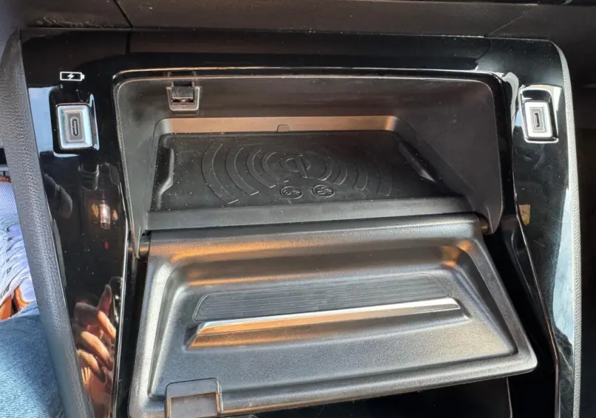 Gros plan sur la console centrale noire du Peugeot 2008 Hybrid 136 e-DCS6 Allure avec compartiment de rangement ouvert.