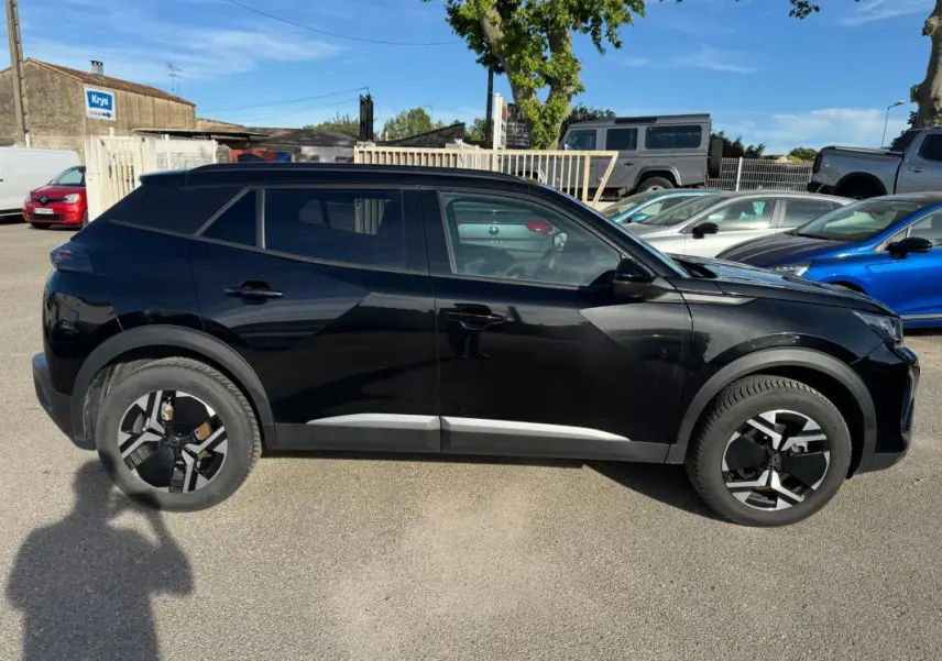 Profil côté gauche du Peugeot 2008 Hybrid 136 Allure noir avec jantes alliage 17 pouces et barres de toit visibles.