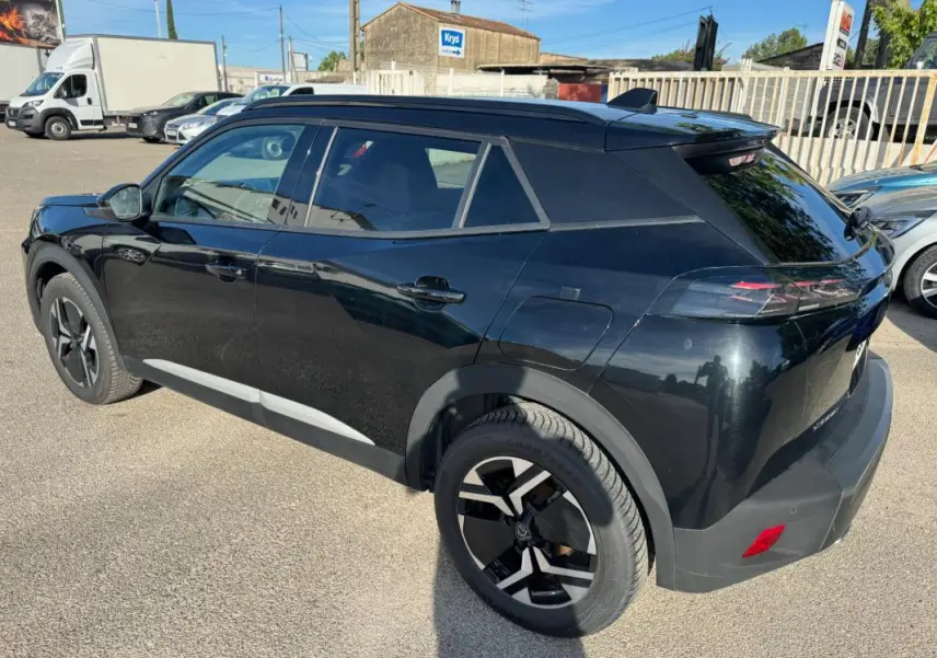 Peugeot 2008 Hybrid noir en 3/4 arrière droit, avec barres de toit et jantes alliage 17 pouces visibles.