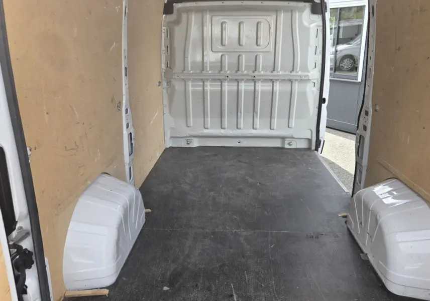Intérieur du fourgon blanc Fiat Ducato MH2 3T 120ch, vue de l’espace de chargement avec cloison pleine et plancher noir.