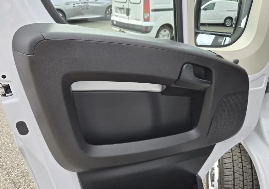 Vue rapprochée de la porte avant droite blanche du FIAT Ducato Fourgon 2023 avec panneau intérieur noir et poignée intégrée.
