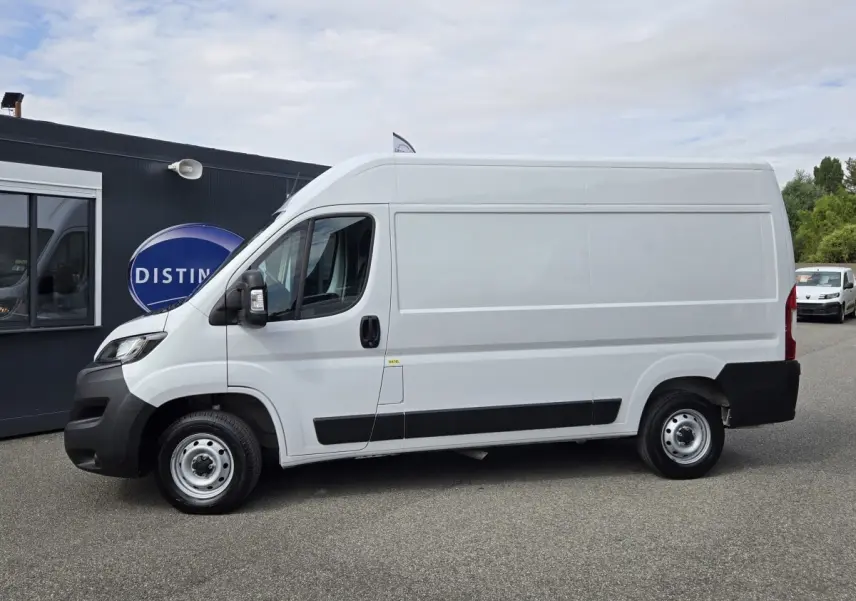 Vue latérale gauche d’un FIAT Ducato Fourgon blanc 2023 avec bas de caisse noir et jantes acier.