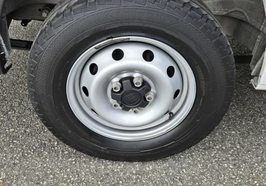 Gros plan sur la roue avant droite du FIAT Ducato Fourgon blanc, avec jante acier et logo central FIAT.