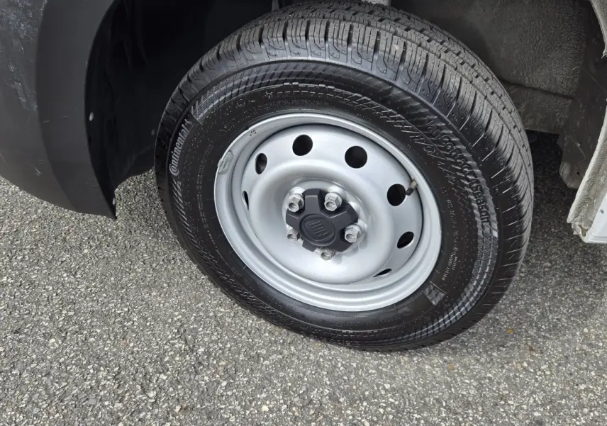 Gros plan sur la roue avant droite du FIAT Ducato Fourgon blanc, jante acier grise avec logo FIAT central.