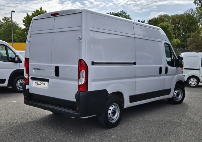 Fiat Ducato Fourgon blanc vu en 3/4 arrière droit, avec cloison pleine et feux arrière rouges.