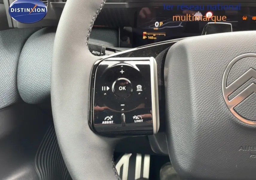 Gros plan sur le volant gris noir du Citroën C5 Aircross 2026, avec commandes intégrées et logo central visible.