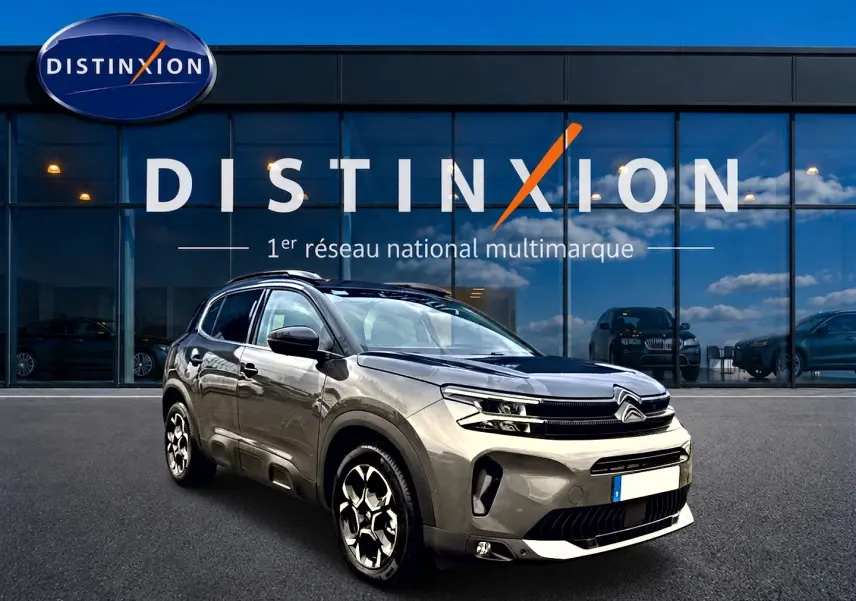 Citroën C5 Aircross gris platinium vue 3/4 avant avec jantes alu et barres de toit devant showroom Distinxion.