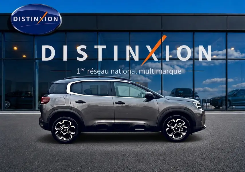 Profil côté gauche du Citroën C5 Aircross gris platinium 2025, avec jantes alu et barres de toit visibles.