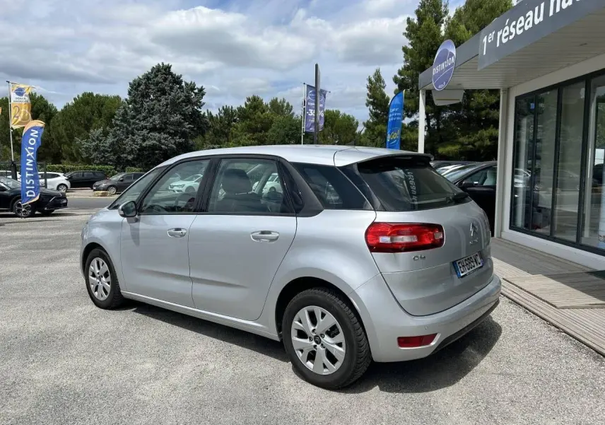 Vue 3/4 arrière droite d'une Citroën C4 Picasso gris aluminum de 2016, avec feux arrière rouges et jantes alliage.