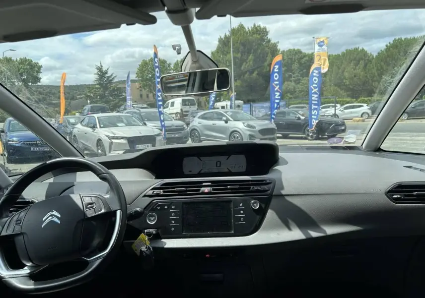 Vue intérieure du tableau de bord et volant du Citroën C4 Picasso gris aluminum, avec écran central et commandes visibles.
