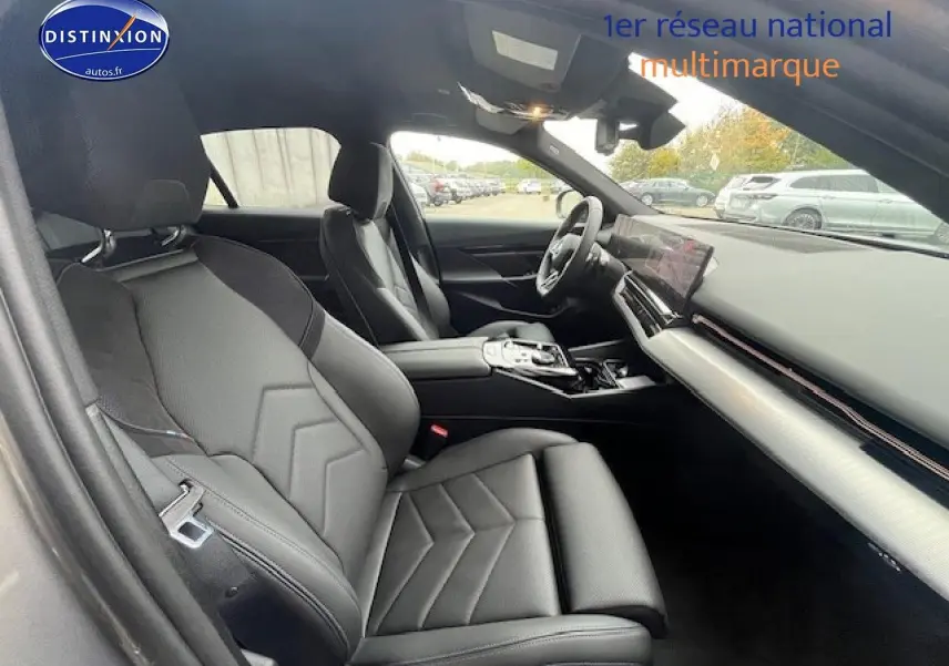 Vue intérieure côté conducteur de la BMW Série 5 gris, sièges sport en cuir et tableau de bord moderne.