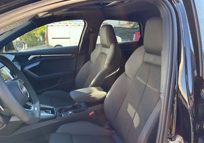 Intérieur noir mythic d'une Audi A3 2025, vue côté gauche sur sièges sport S-Line en cuir et volant cuir méplat.