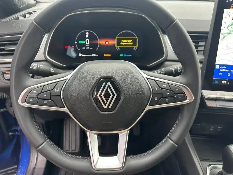 Vue rapprochée du volant multifonction noir avec logo Renault et tableau de bord numérique du Captur 2025.