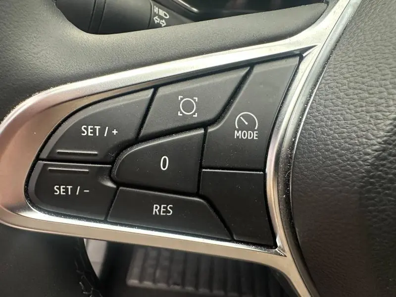 Gros plan sur les commandes de régulateur de vitesse au volant du Renault Captur 1.6 E-Tech bleu Iron/Noir Etoilé.