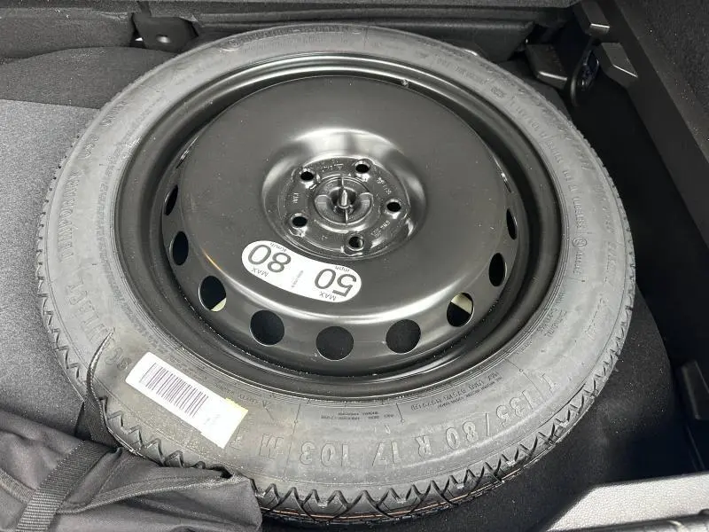 Pneu de secours noir dans le coffre du Renault Captur 1.6 E-Tech full hybrid 2025, vue de dessus.