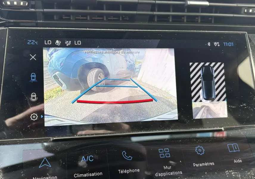 Écran tactile intérieur montrant la caméra de recul avec vue sur roue arrière gauche d’une Peugeot 308 Bleu Obsession.