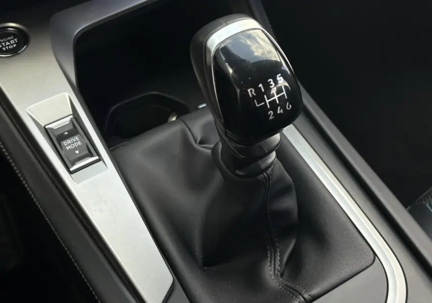 Gros plan sur le levier de vitesses manuel noir et la commande Drive Mode dans l’habitacle d’une Peugeot 308 2024.
